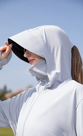 Woman wearing a grey sun protection jacket, hood pulled up, and sunglasses.