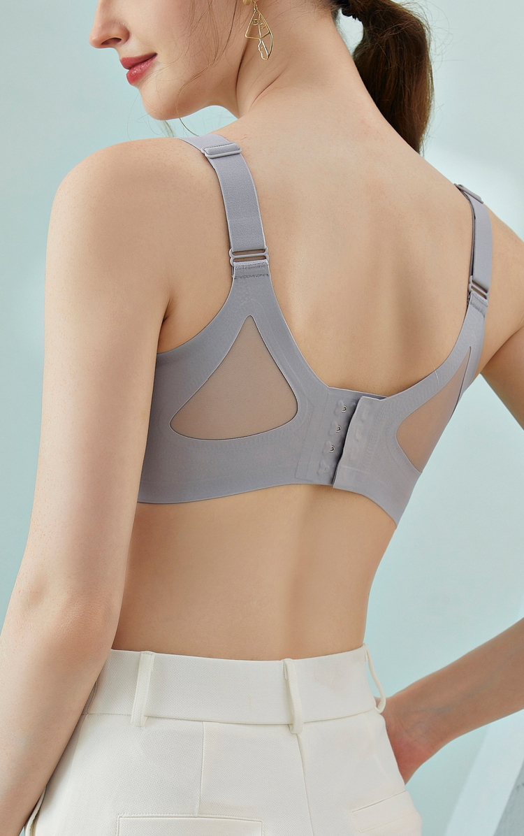 A back view of a model wearing a gray wireless bra, highlighting the wide back smoothing sidebands and breathable mesh back.