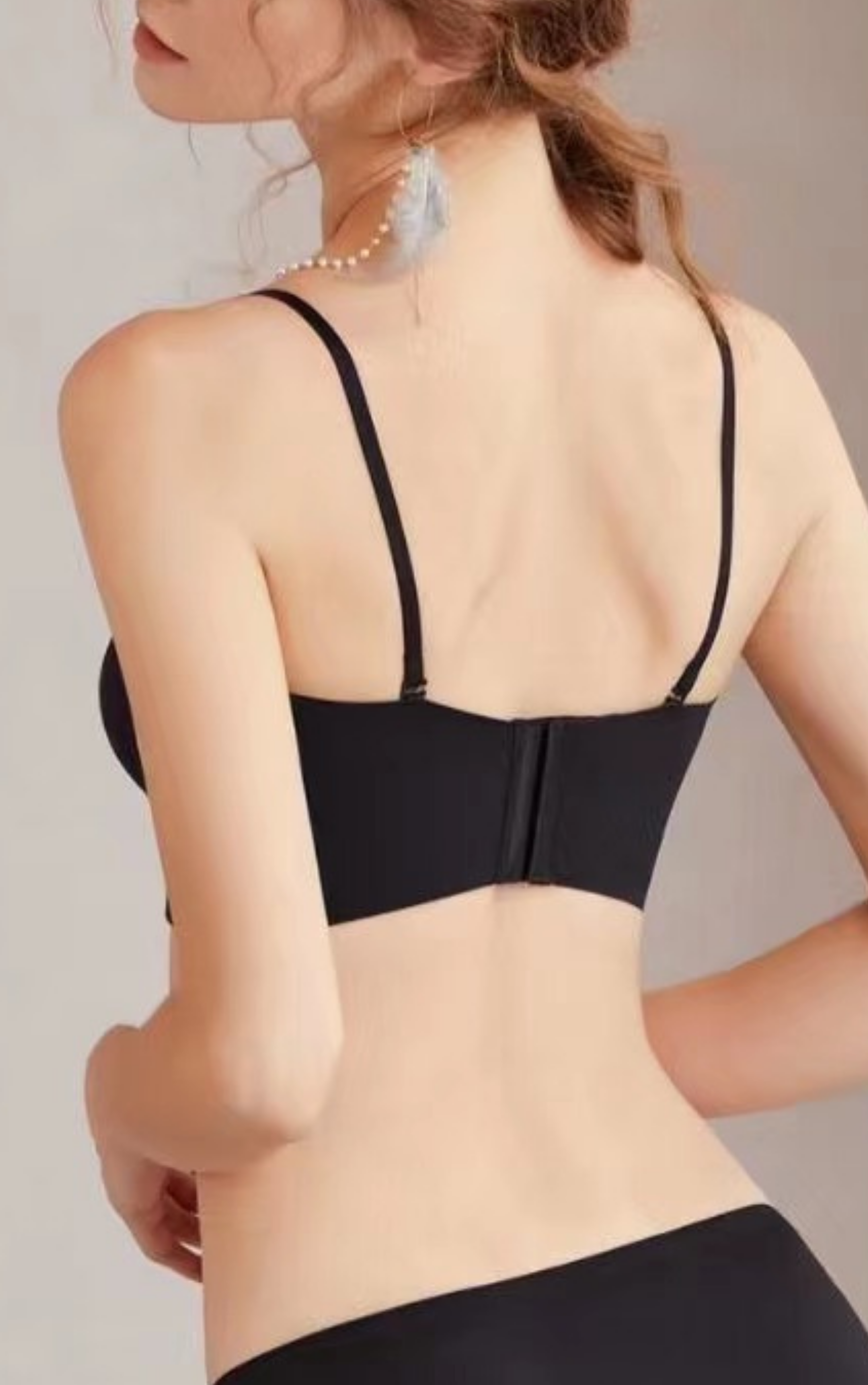 Back view of a woman wearing a black strapless bra, highlighting the wide sidebands and seamless fit.