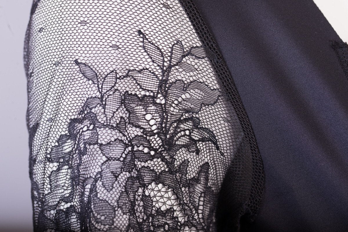 Angled view of black firm-control lace romper shapewear with Italian fabric for all-day comfort